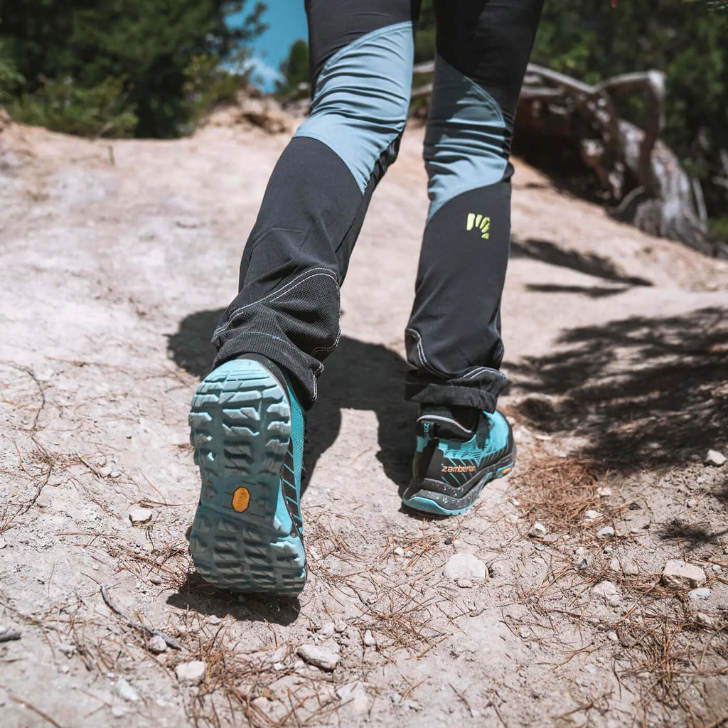 Person wearing blue hiking shoes and black pants on a trail