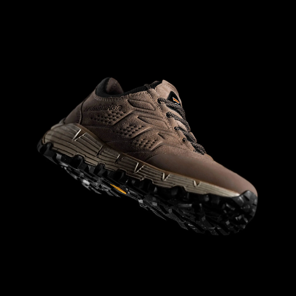 Brown hiking shoe with a textured sole on a black background