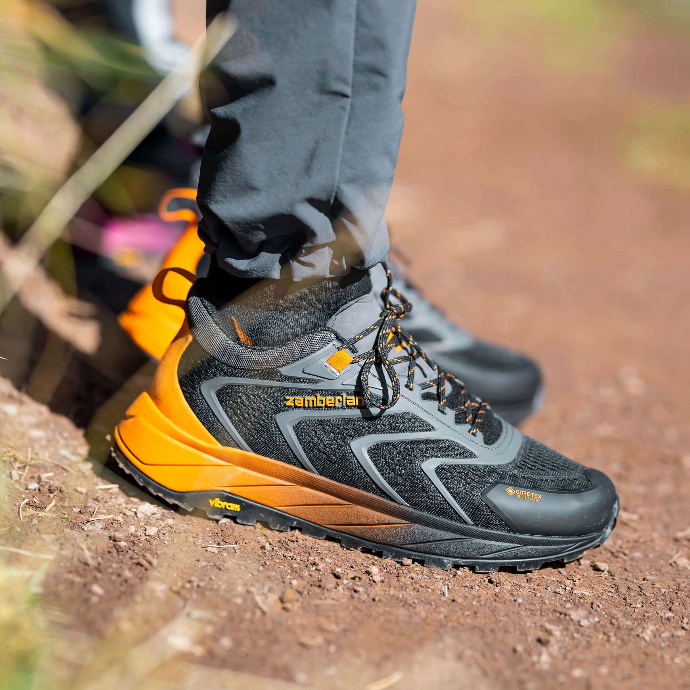 Hiking shoes with orange and black design on a natural ground