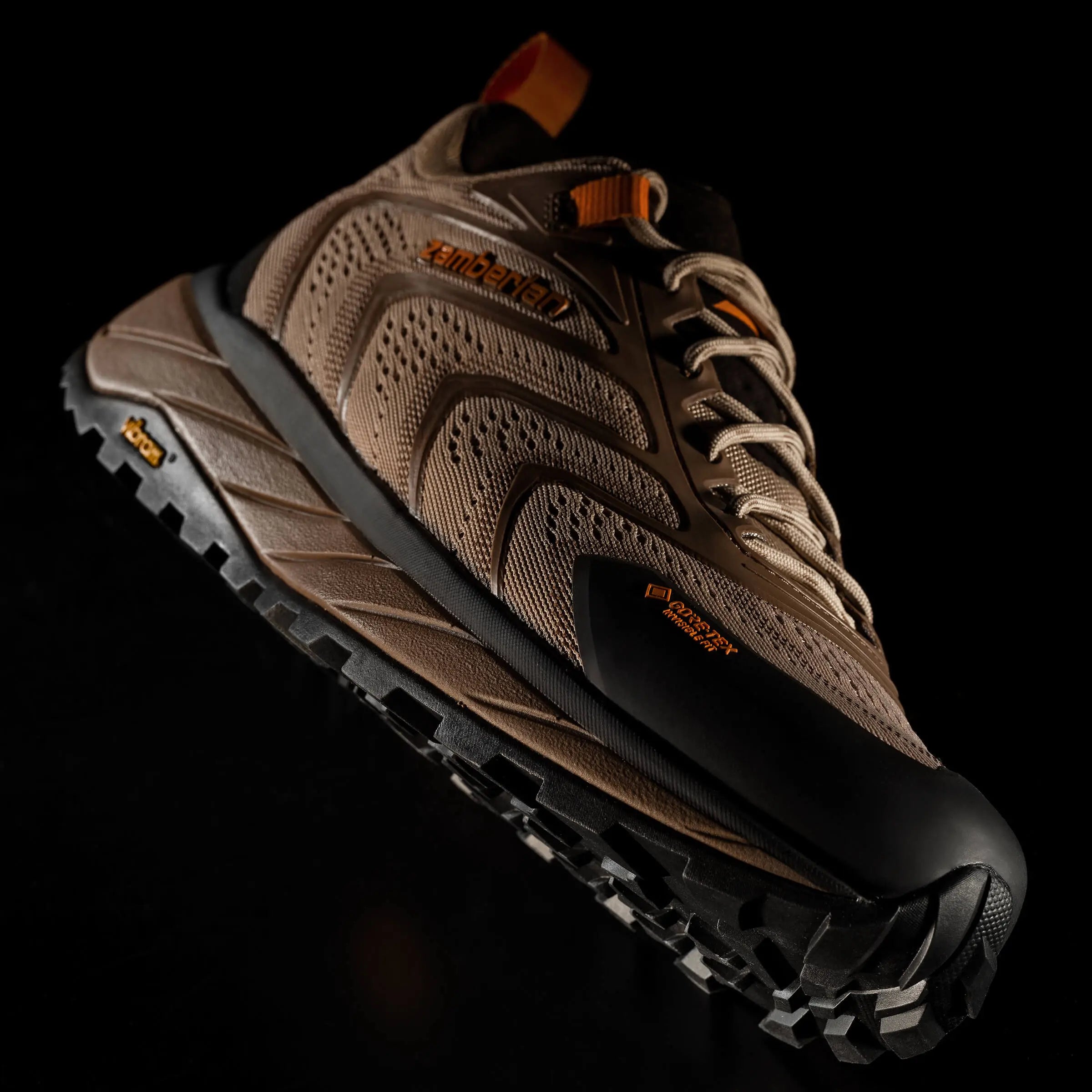 Brown hiking shoe with black sole on a dark background
