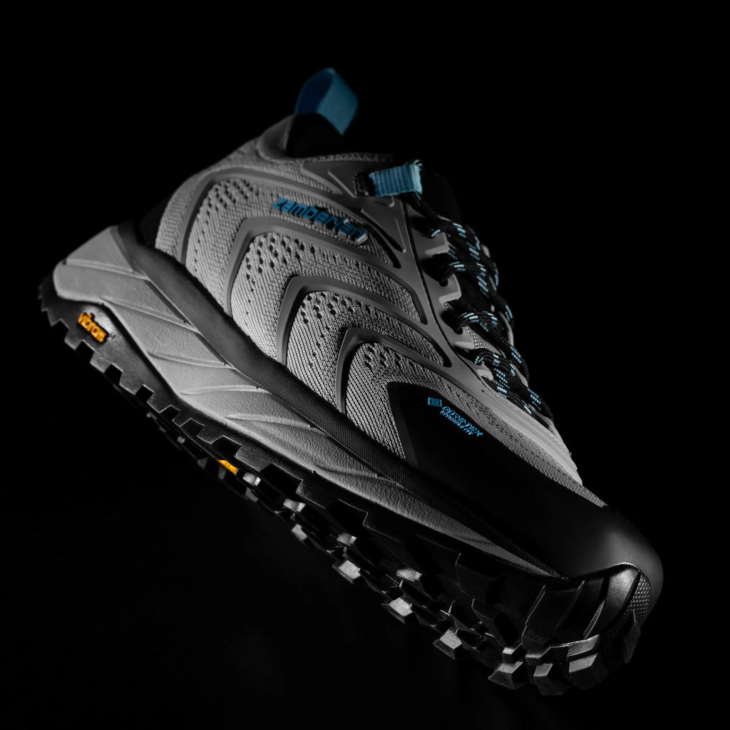 Black and grey hiking shoe with textured sole on a black background