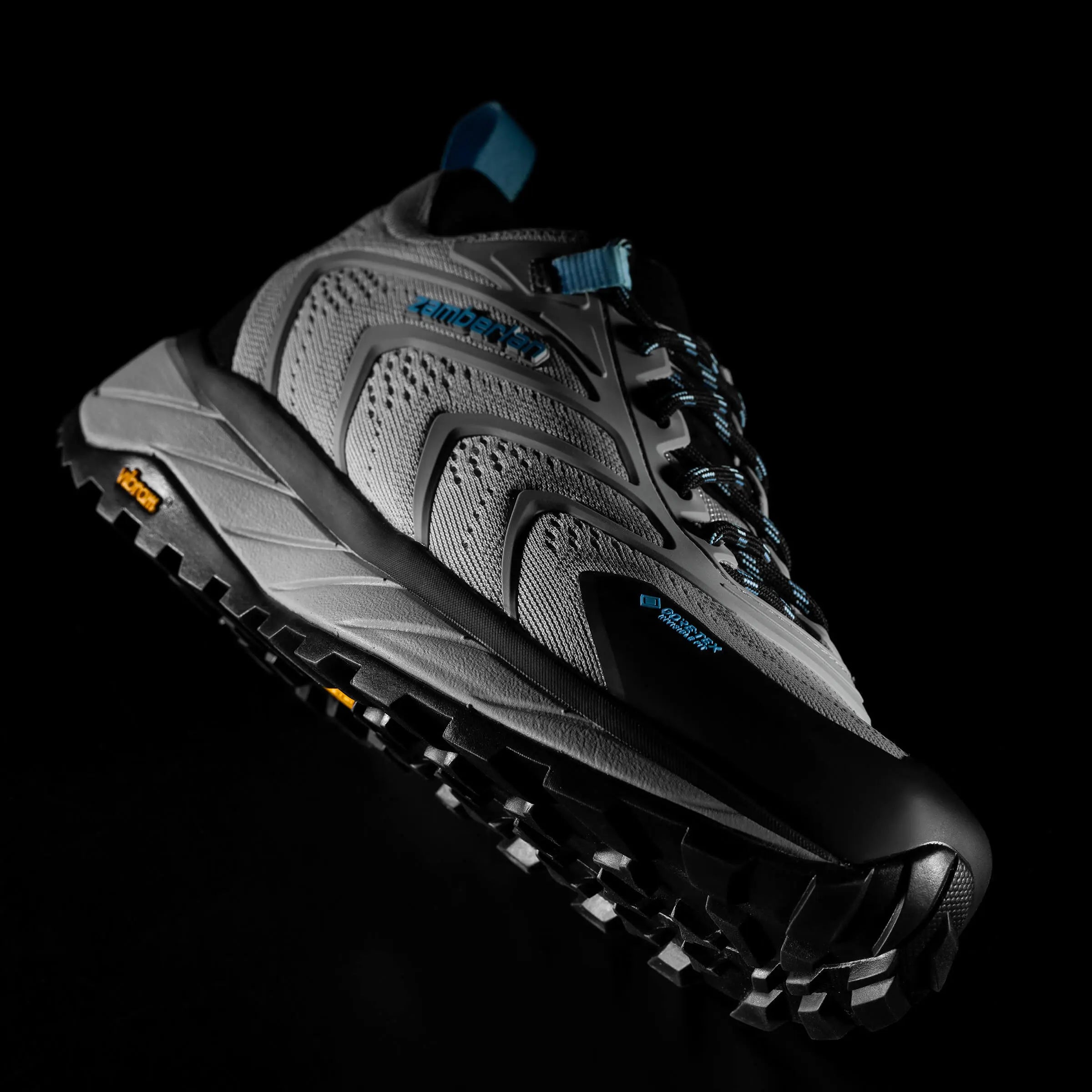 Black and grey hiking shoe with textured sole on a black background