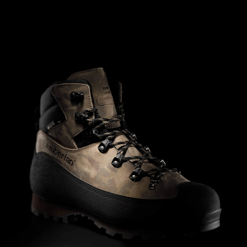 Brown hiking boot with black sole on a black background