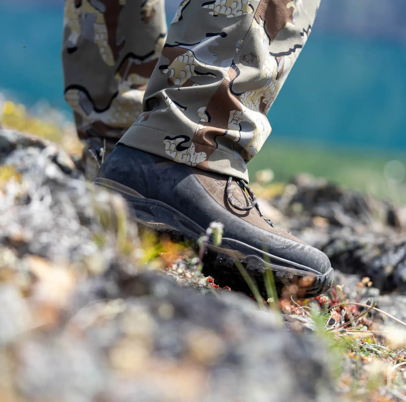 Close-up of hiking boots on a rocky terrain with a blurred natural background