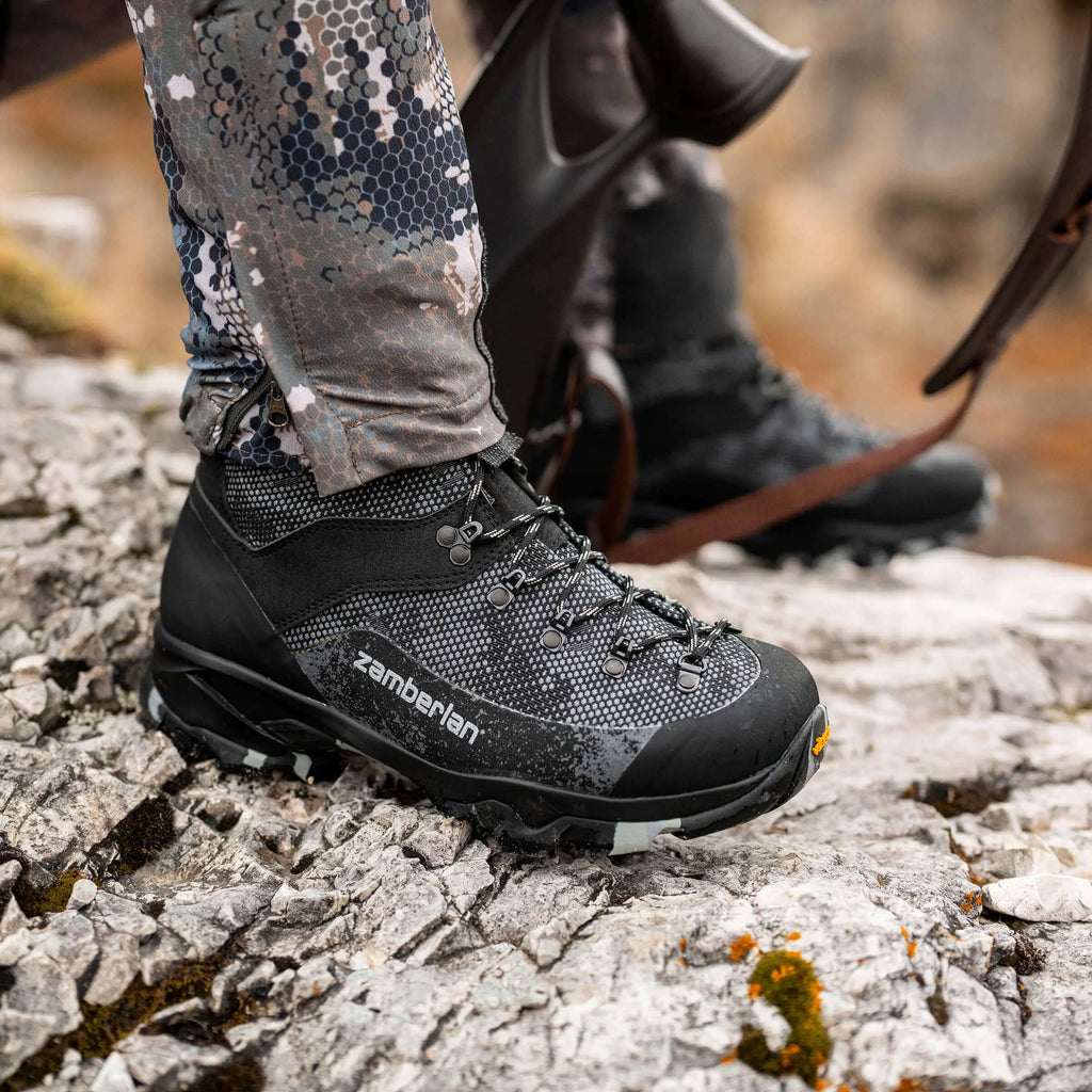 Black hiking boot with 'zamberlan' branding on a rocky surface