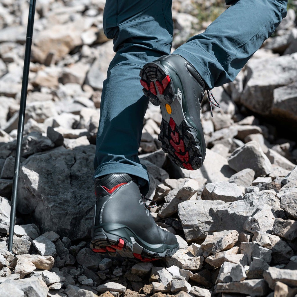 Person wearing hiking boots with red accents on rocky terrain