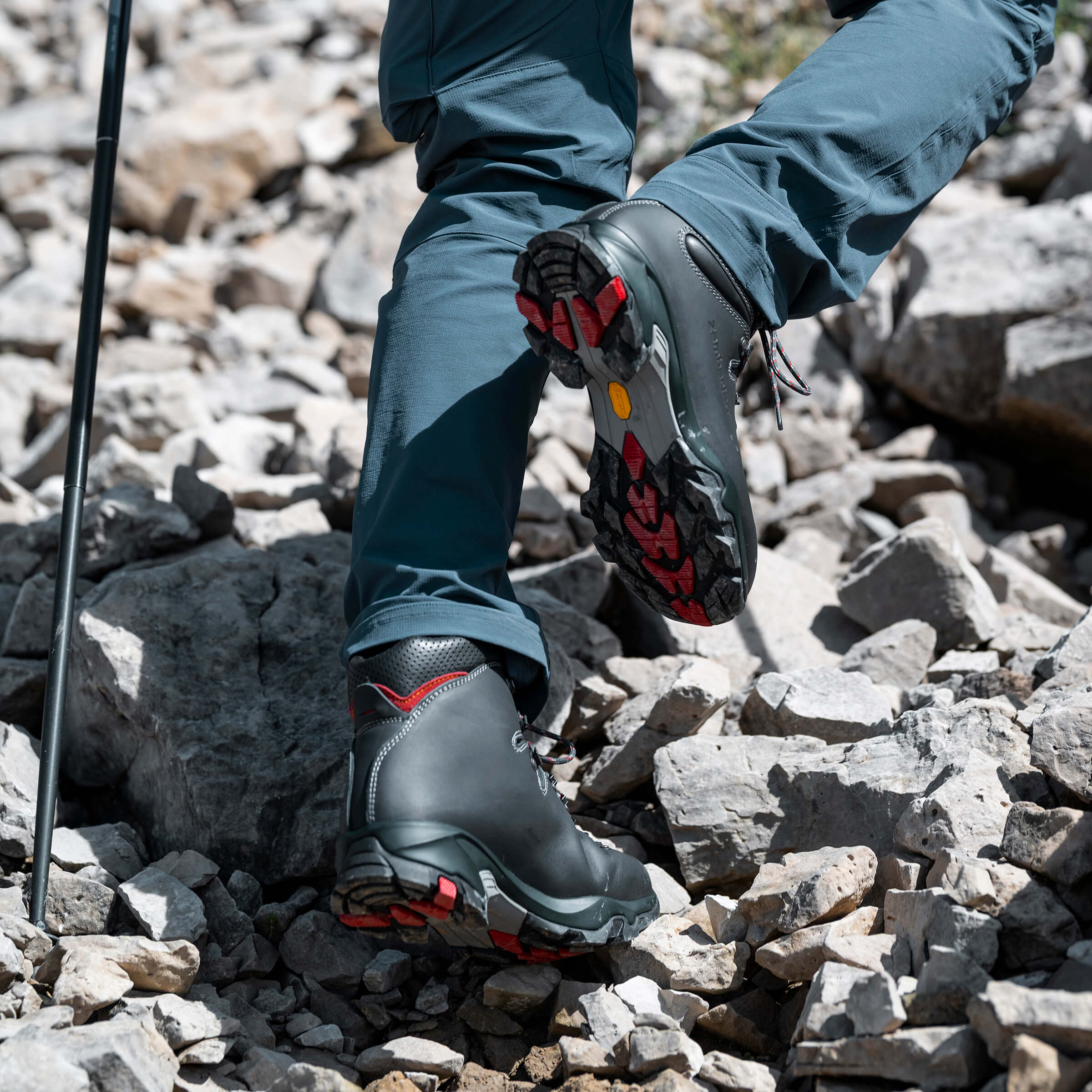 Person wearing hiking boots with red accents on rocky terrain