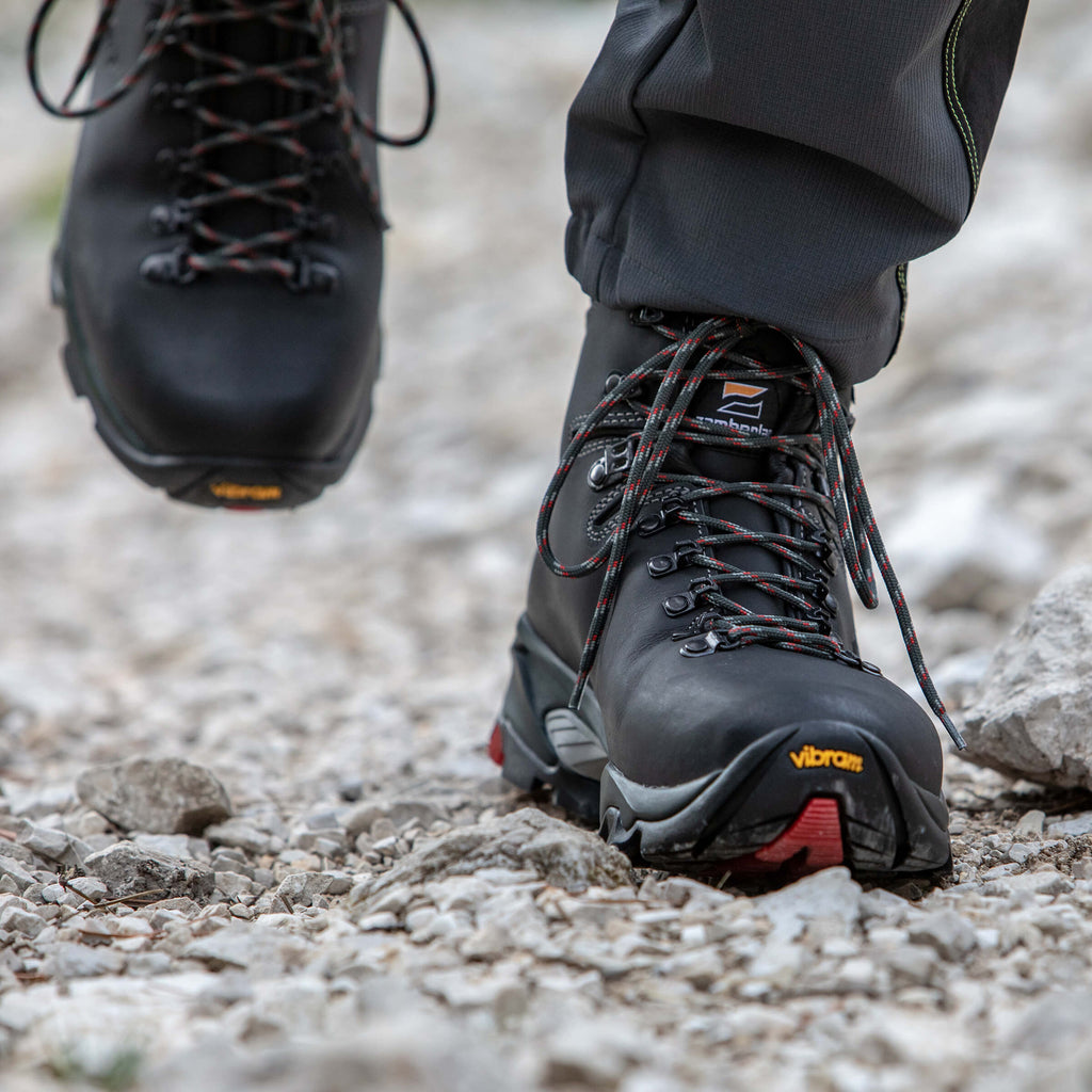 Close-up of black hiking boots with Vibram sole on a rocky ground