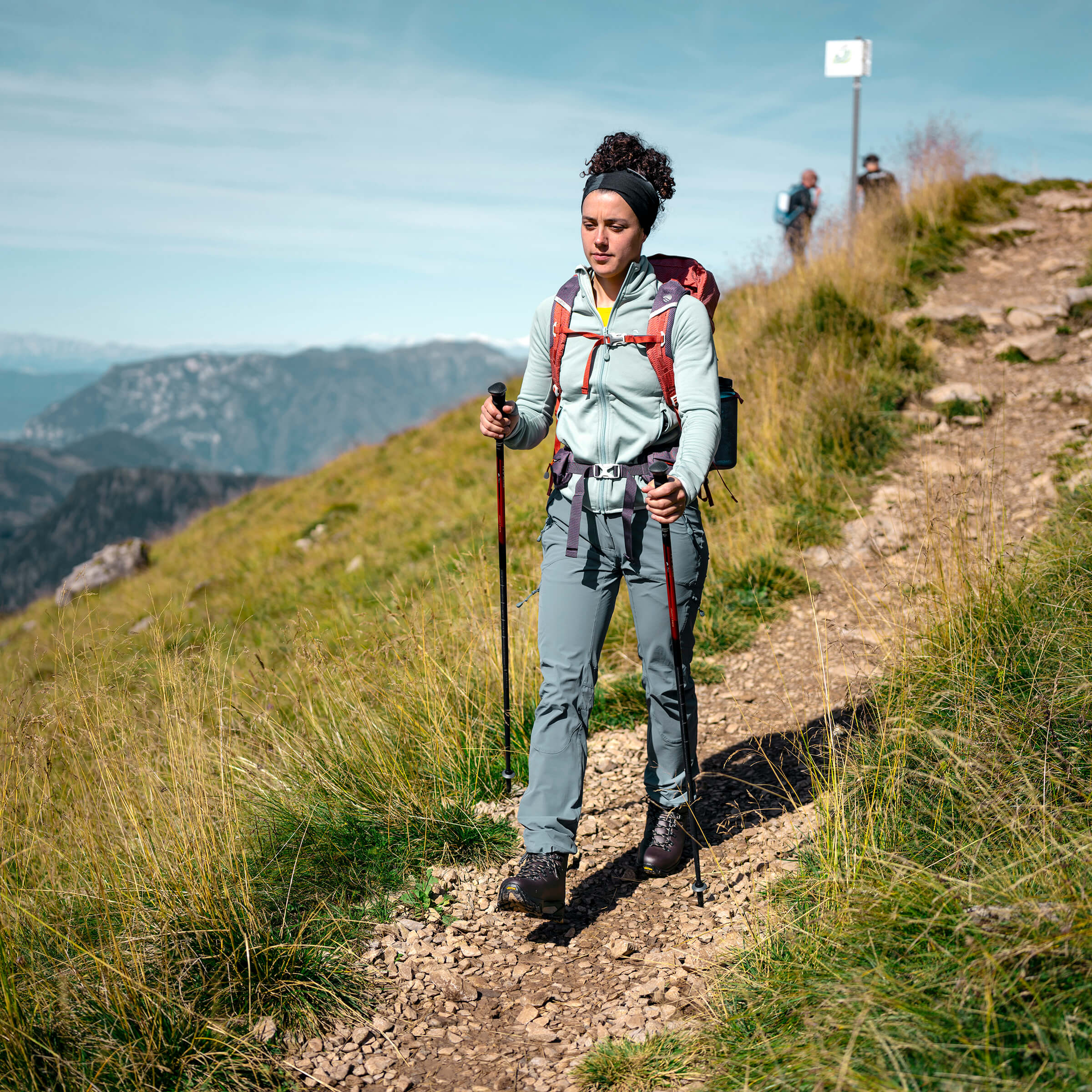 Woman hiking on a mountain trail with backpack and trekking poles