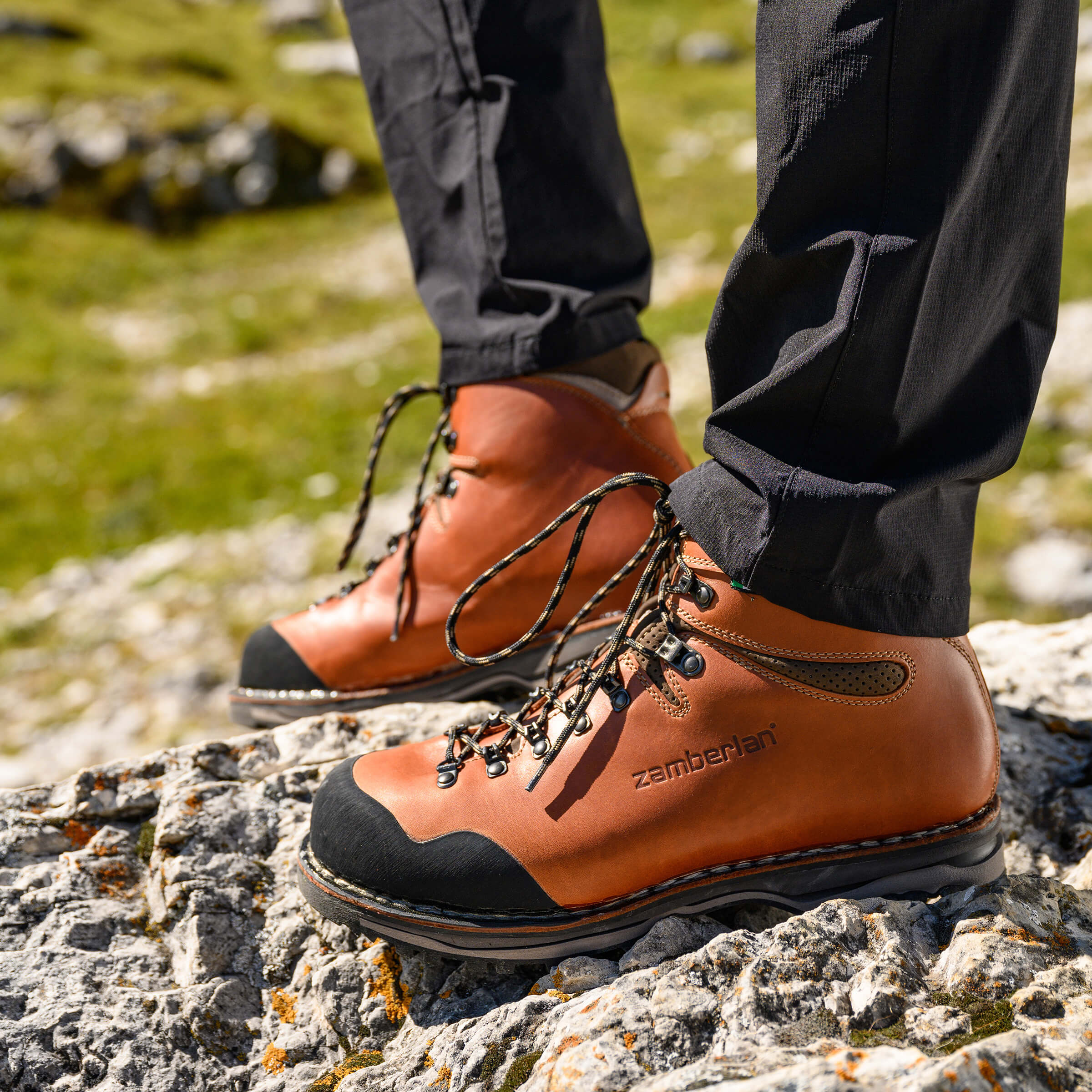 Brown hiking boots with black soles on a rocky surface, brand 'Zamberlan' visible.