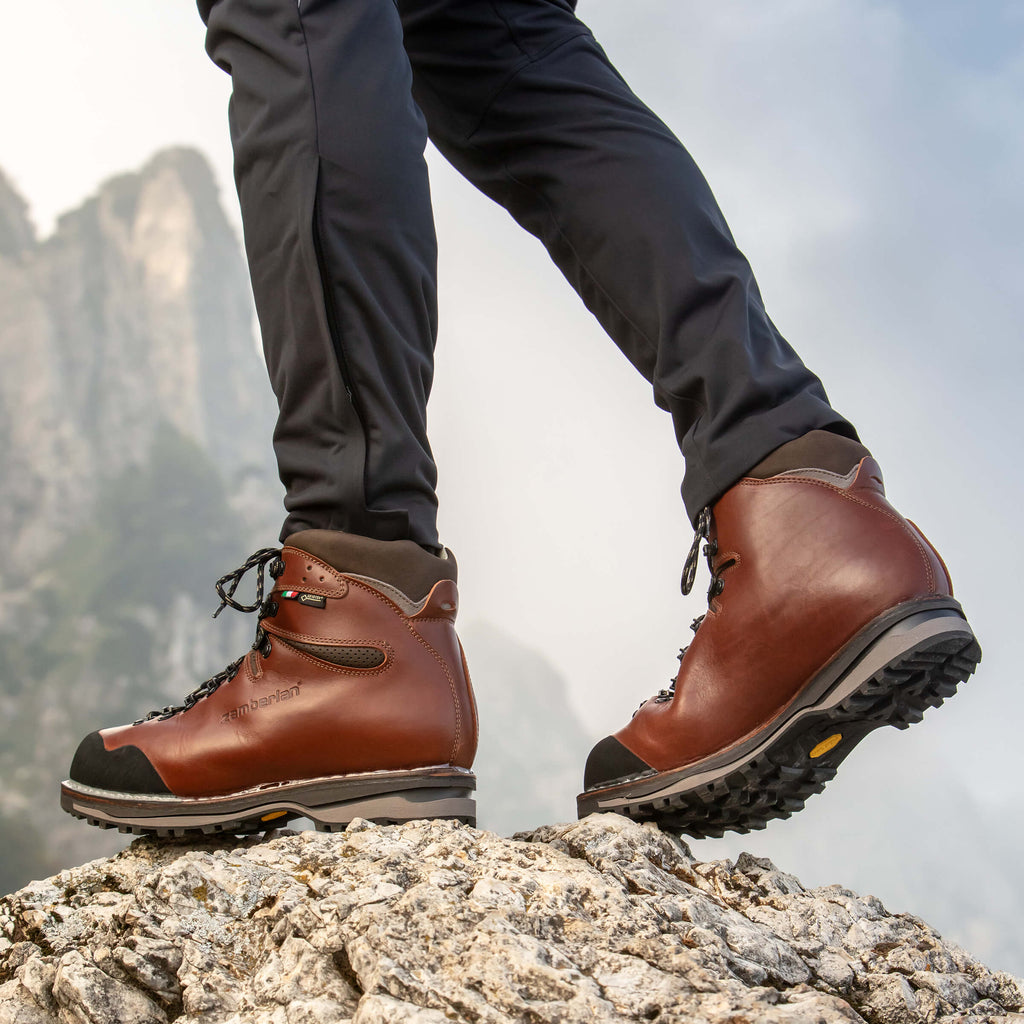 Brown hiking boots on a rocky surface with a mountainous background