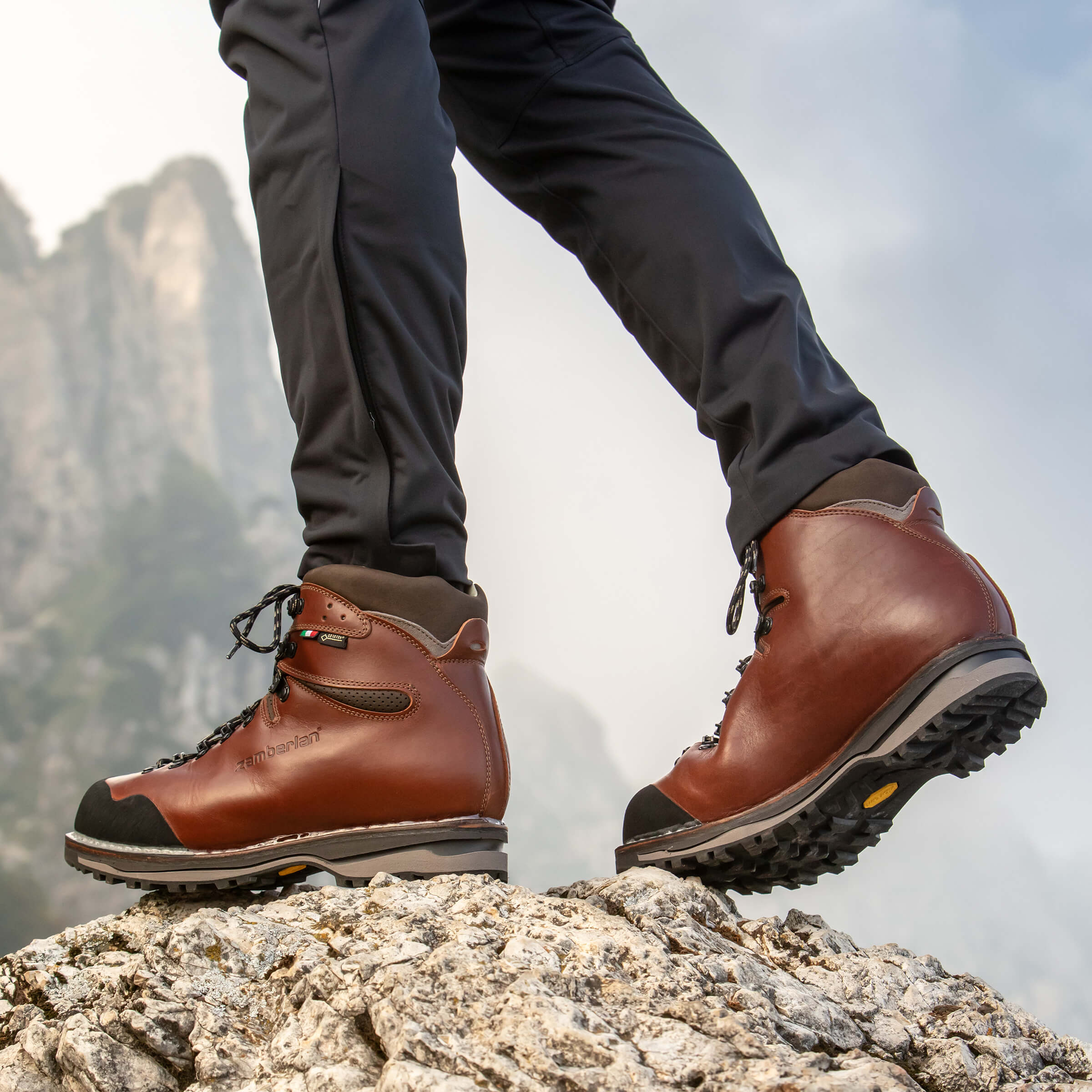 Brown hiking boots on a rocky surface with a mountainous background