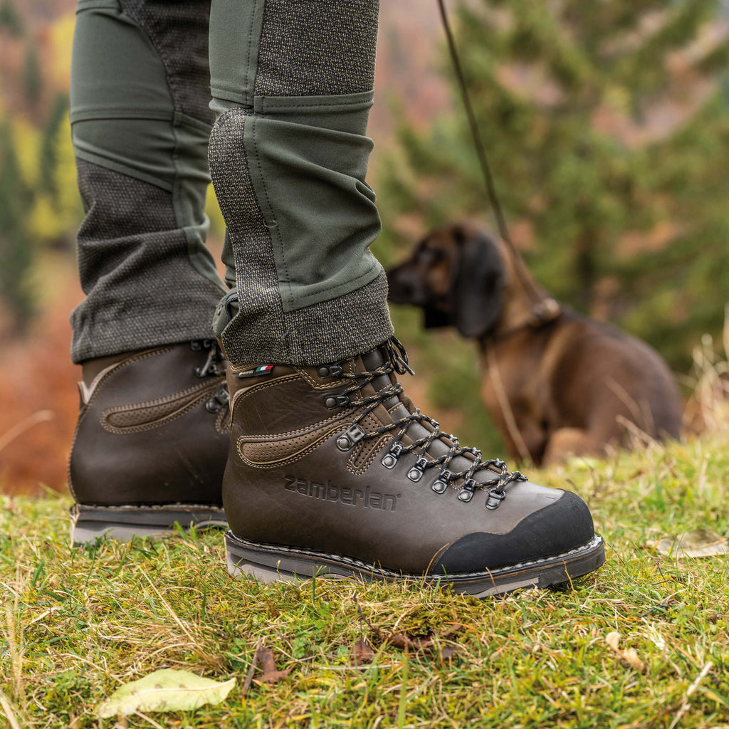 Brown hiking boots with visible brand name on grass with a dog in the background