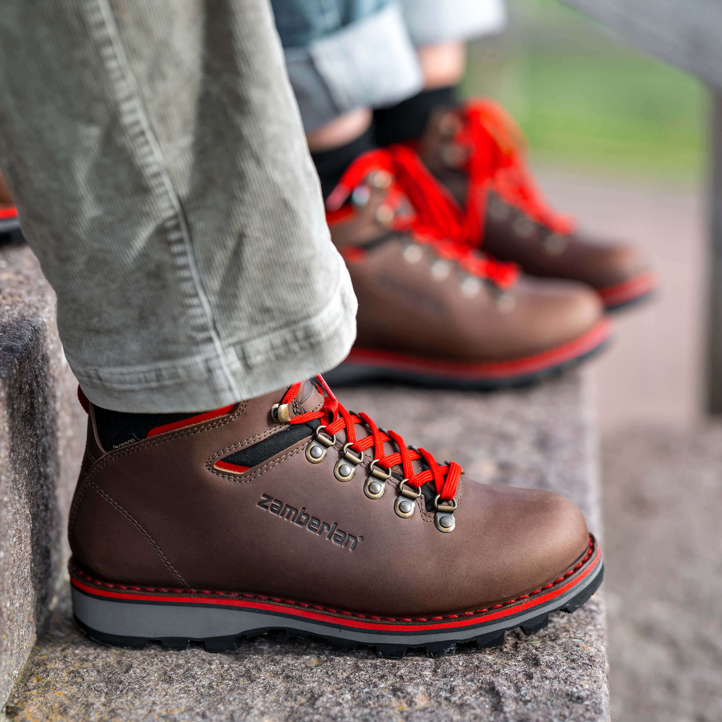 Brown hiking boots with red laces and Zamberlan branding on a stone surface.