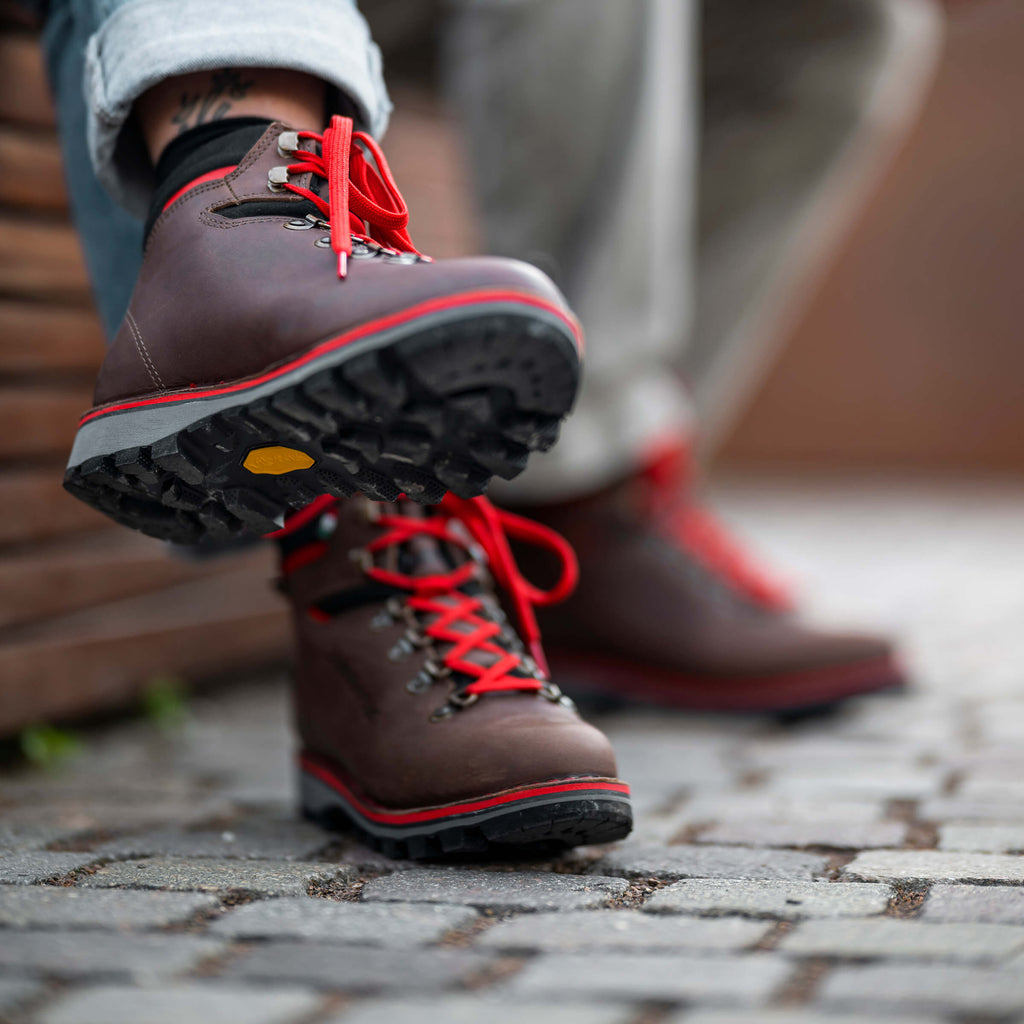 Brown hiking boots with red laces on a stone pavement