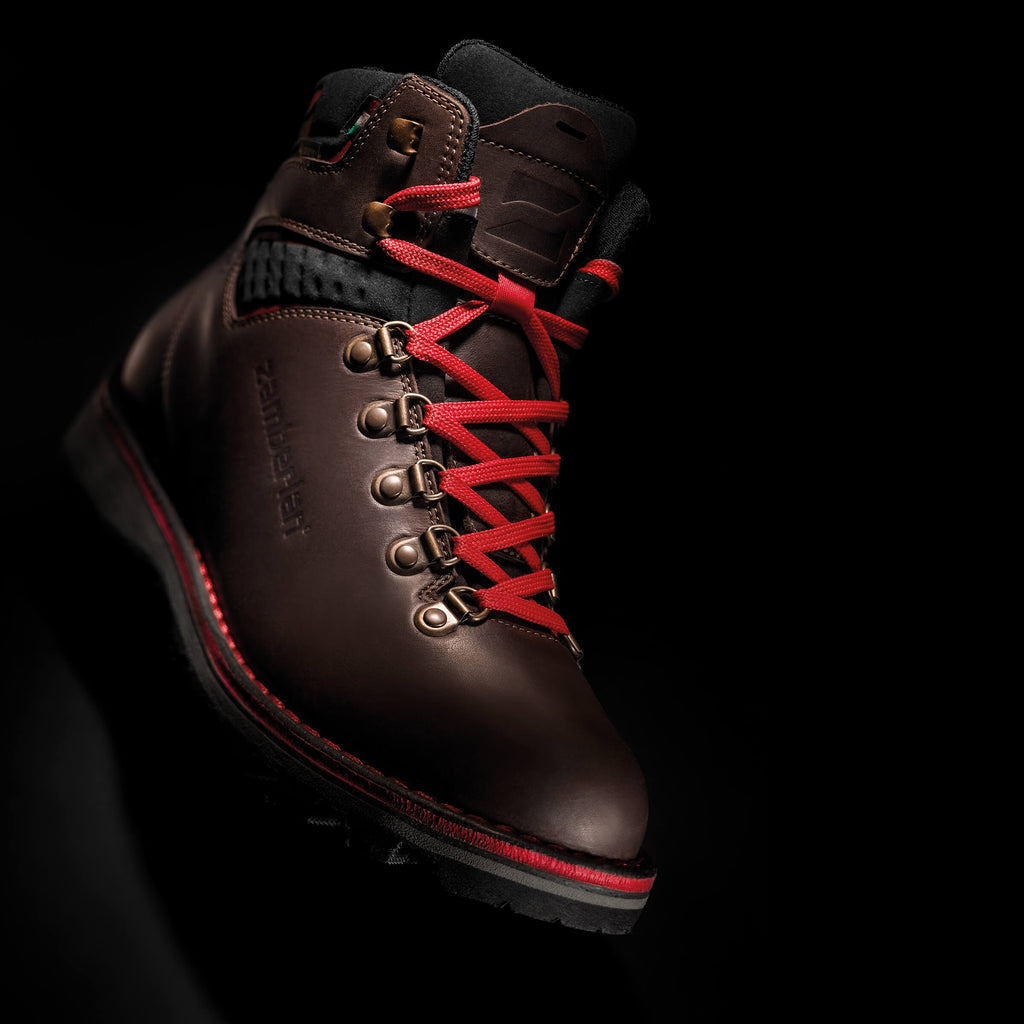 Brown boot with red laces on a black background