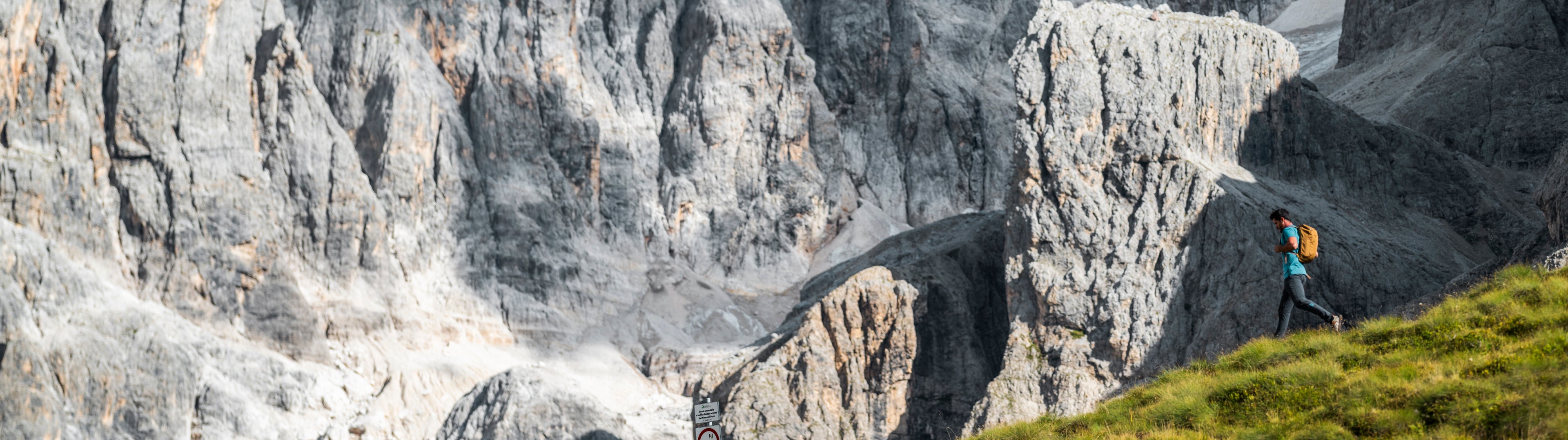 Person hiking on a rocky mountain trail with steep cliffs.