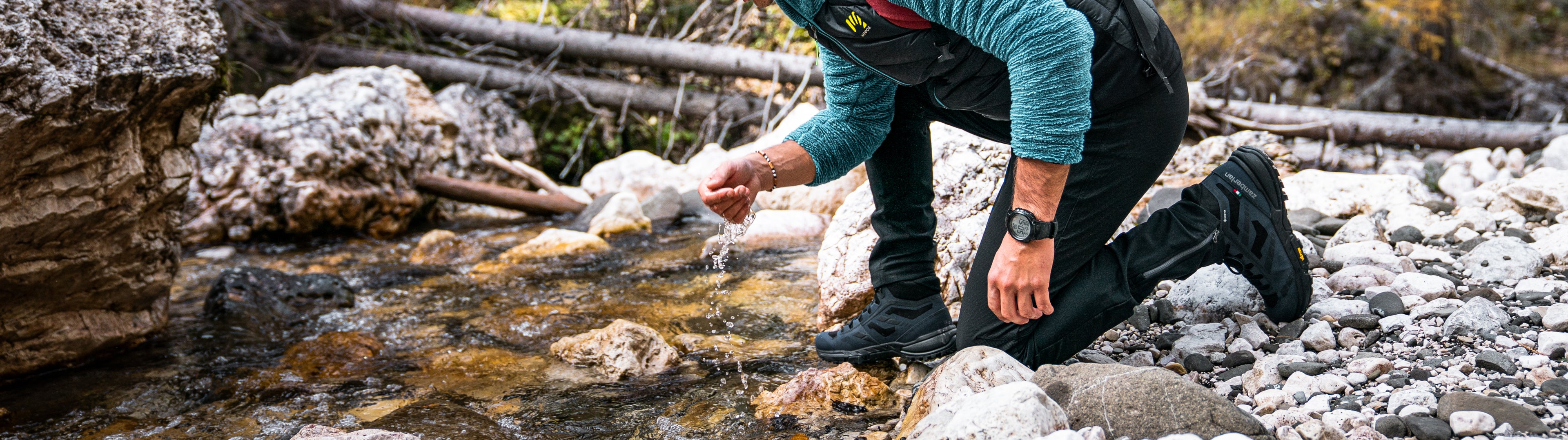 Person touching water by a stream in a natural setting