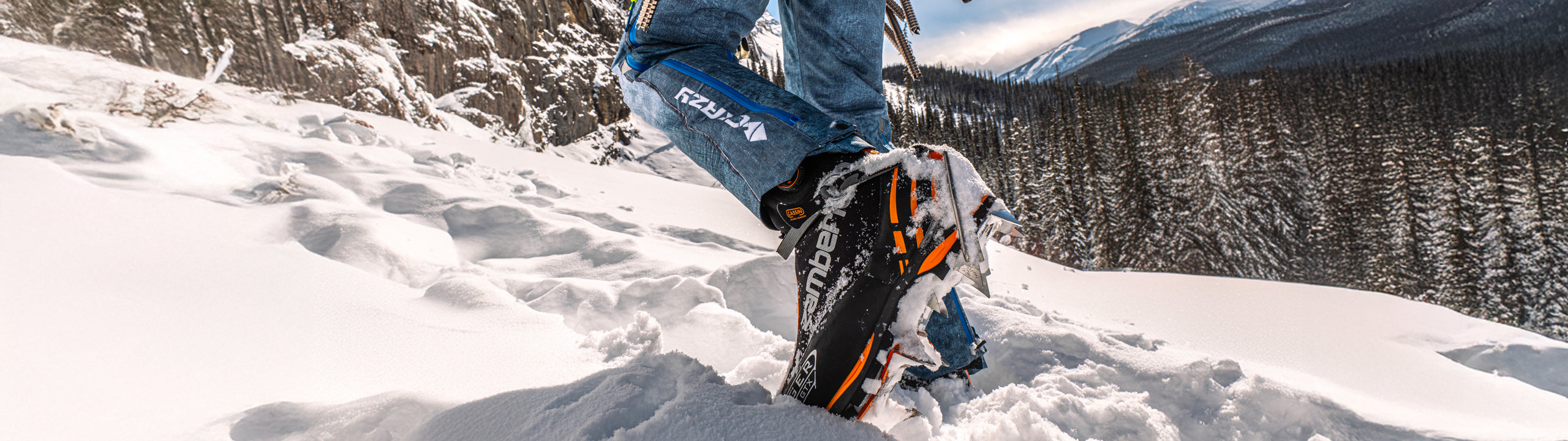 Person wearing snowshoes on a snowy landscape with mountains in the background