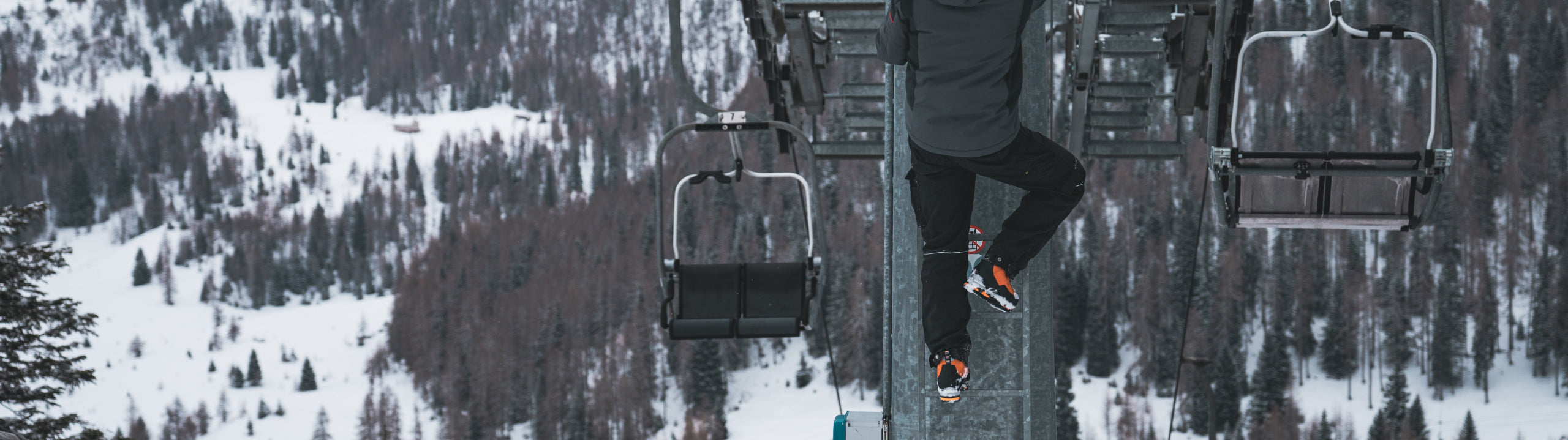 Person on a ski lift with a snowy landscape and trees below