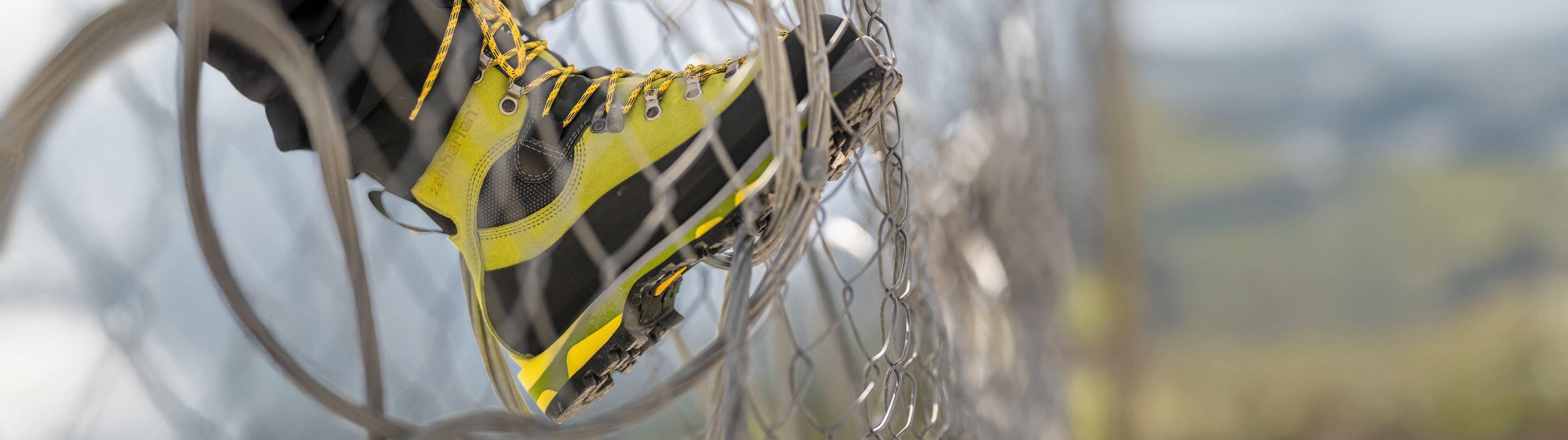 Close-up of yellow climbing shoes with crampons on a blurred mountain background