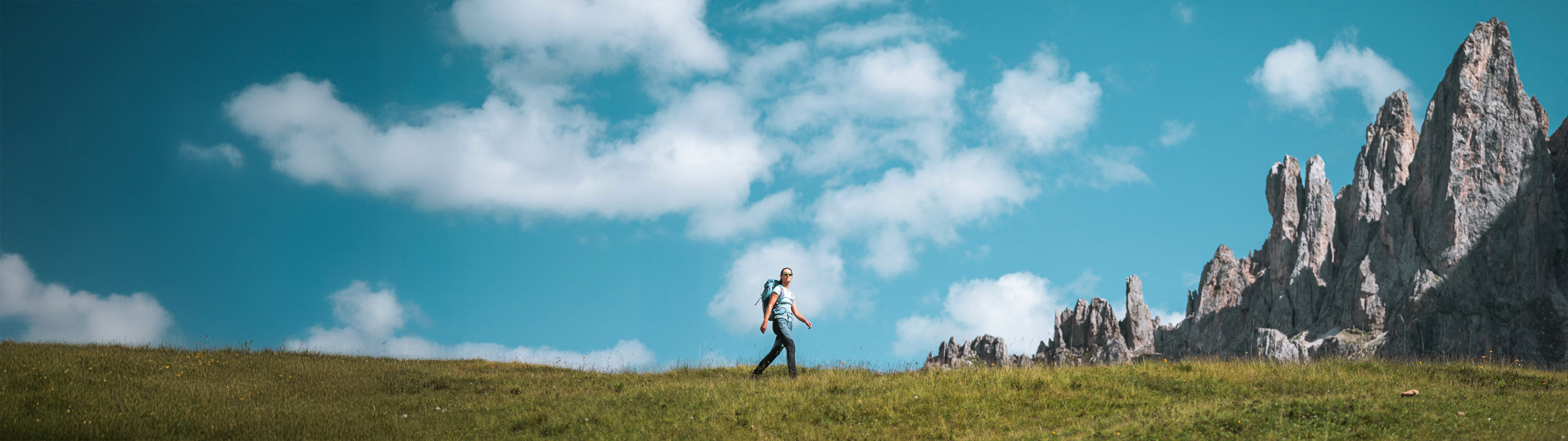 Person hiking in a mountainous landscape with a clear blue sky